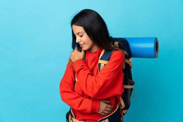 Junge Bergsteigerfrau mit Rucksack, die unter Schulterschmerzen leidet, weil sie sich Mühe gegeben hat