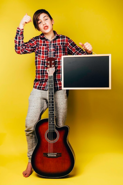 Junge bleibt mit Gitarre und Tafel mit Kopierraum