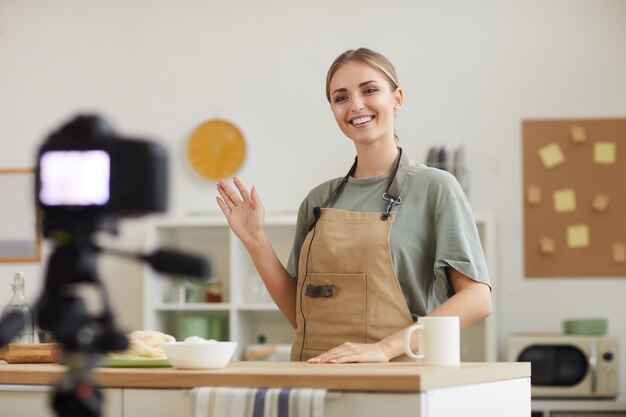 Junge Bloggerin lächelt und dreht das Video, das sie lehrt, online zu kochen