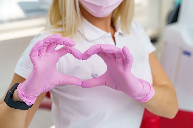 Junge blonde Chirurg Arzt Frau über isolierte Hintergrund lächelnd in der Liebe zeigt Herzsymbol und Form mit den Händen.
