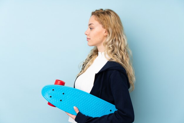 Junge blonde Frau auf Blau mit einem Schlittschuh