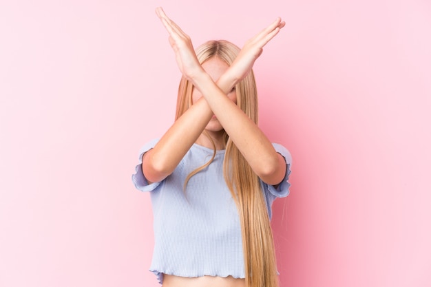 Junge blonde Frau auf rosa Wand, die zwei Arme verschränkt hält, Verweigerungskonzept.