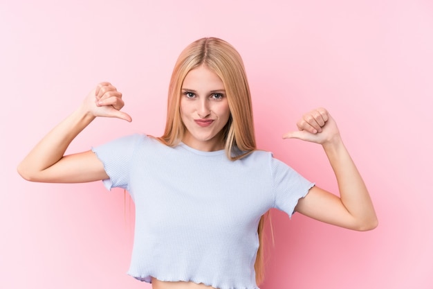 Junge blonde Frau auf rosa Wand fühlt sich stolz und selbstbewusst, Beispiel zu folgen.