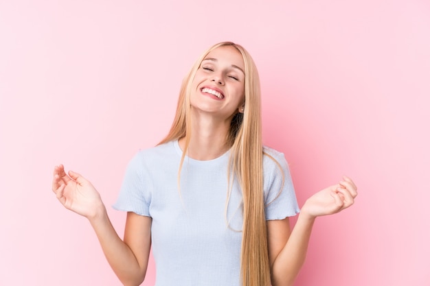 Junge blonde Frau auf rosafarbenem Hintergrund froh, viel lachend. Glück-Konzept.