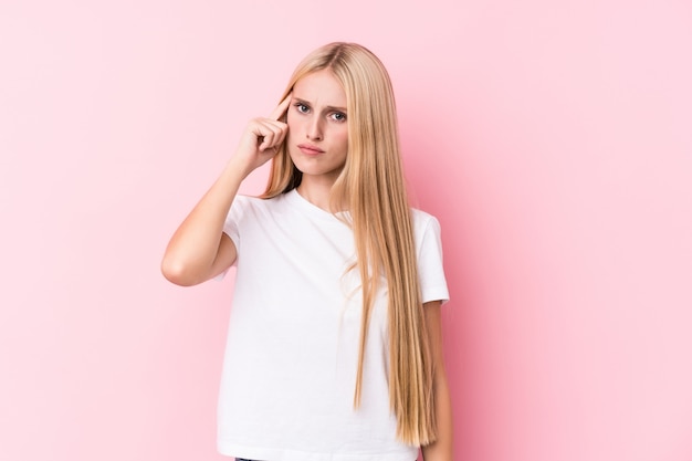 Junge blonde Frau auf rosafarbener Wand Tempel mit dem Finger zeigend und denken, gerichtet auf eine Aufgabe.