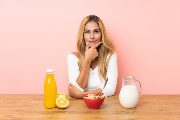 Junge blonde Frau, die das Frühstücksmilchlachen hat