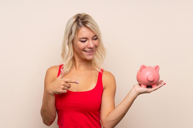 Junge blonde Frau, die ein großes piggybank anhält