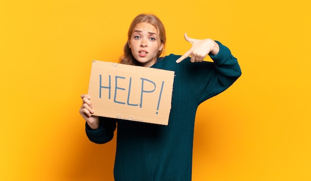 Foto junge blonde frau, die ein schild mit worthilfe hält.