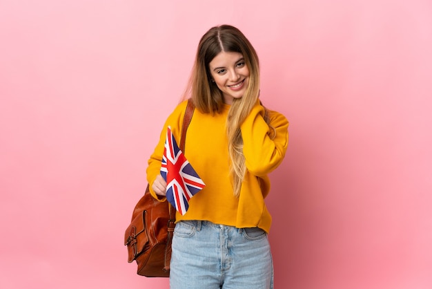 Junge blonde Frau, die eine britische Flagge lokalisiert auf weißem Hintergrund lachend hält