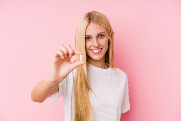 Junge blonde Frau, die einige Pillen getrennt auf einem blackground nimmt