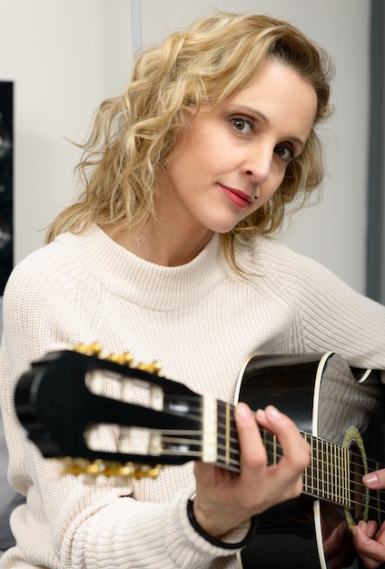 Junge blonde Frau, die Gitarre spielt