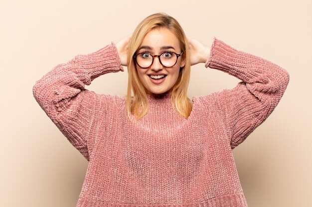 Foto junge blonde frau, die sich gestresst, besorgt, ängstlich oder ängstlich fühlt, mit händen auf dem kopf, die bei einem fehler in panik geraten