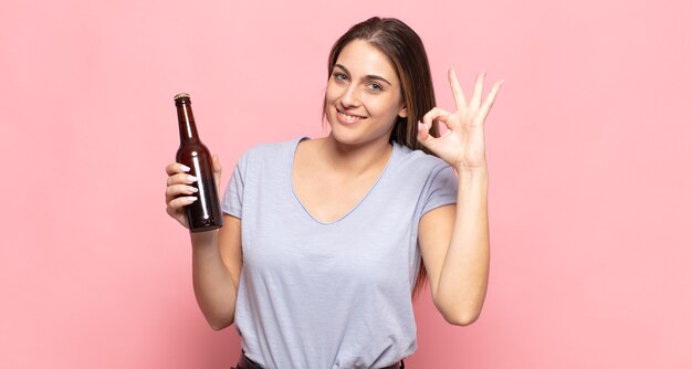 Junge blonde Frau, die sich glücklich, entspannt und zufrieden fühlt, Zustimmung mit okayer Geste zeigt und lächelt
