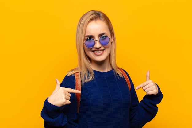 Junge blonde Frau, die stolz, arrogant, glücklich, überrascht und zufrieden aussieht, auf sich selbst zeigt und sich wie ein Gewinner fühlt