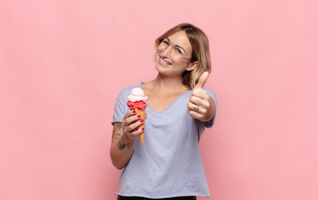 Junge blonde Frau, die stolz, sorglos, selbstbewusst und glücklich fühlt und positiv mit Daumen hoch lächelt