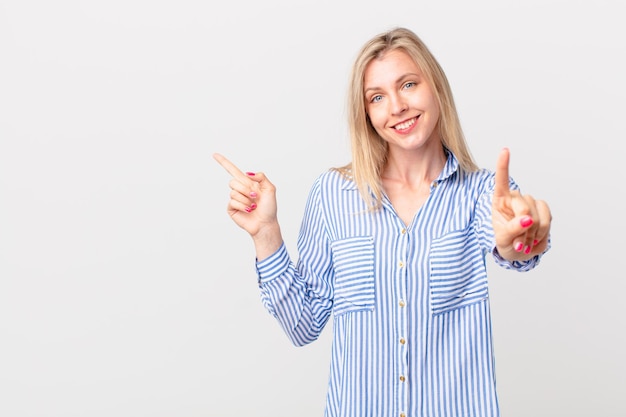 Junge blonde Frau, die stolz und selbstbewusst lächelt, macht die Nummer eins