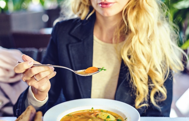 Junge blonde Frau, die Suppe mit Gemüse isst