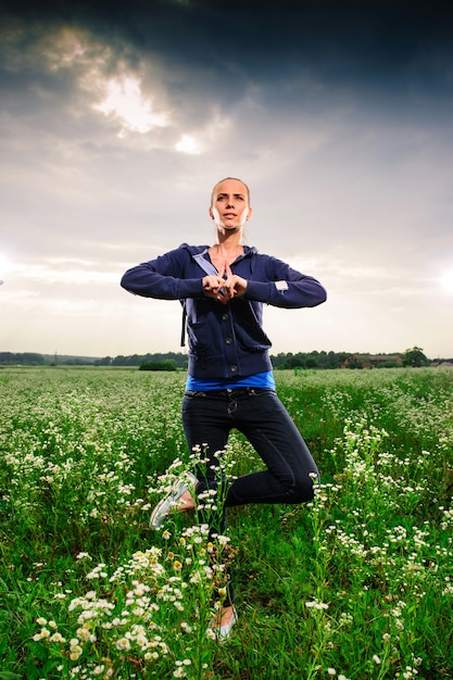 Junge blonde Frau, die Yoga auf einer Wiese tut