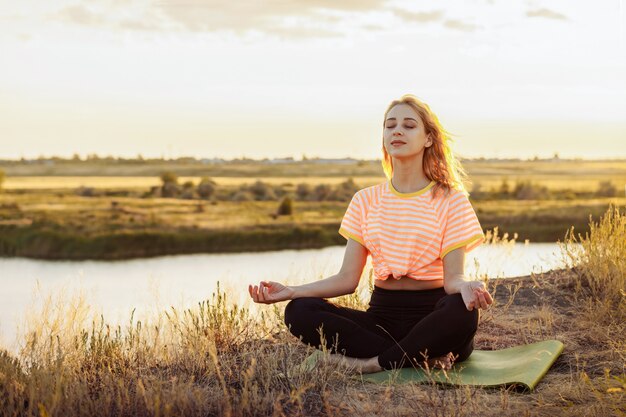 Junge blonde Frau, die Yoga draußen macht