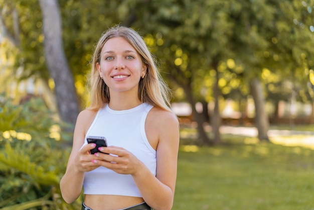 Junge blonde Frau im Freien, die mit dem Handy eine Nachricht sendet