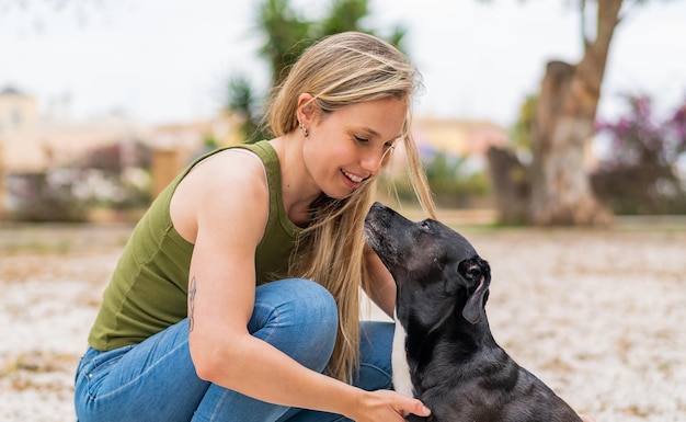 Junge blonde Frau im Freien mit ihrem entzückenden schwarzen Hund