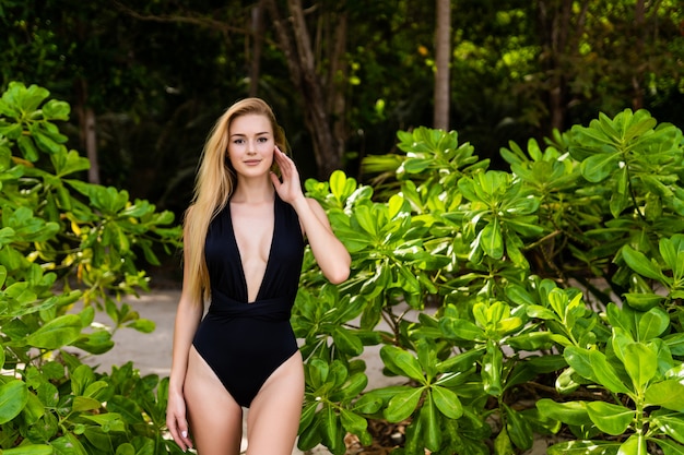 Junge blonde Frau in einem Bikini auf einem Hintergrund von Palmen