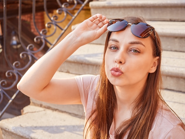 Foto junge blonde frau in einem rosa t-shirt auf der treppe