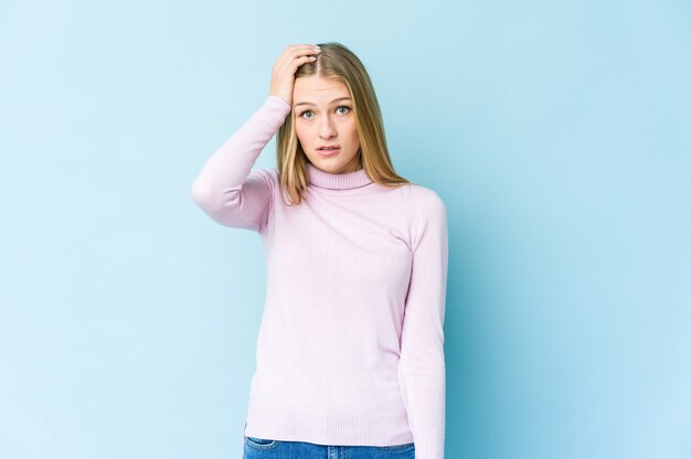 Junge blonde Frau isoliert auf blauem Hintergrund schockiert, hat sie sich an wichtige Treffen erinnert.