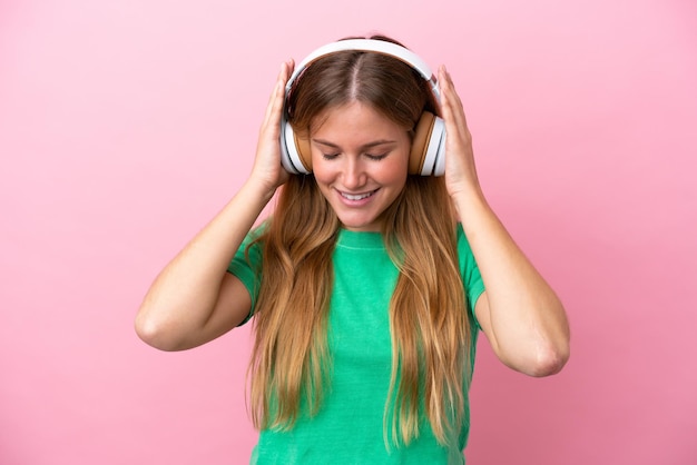 Junge blonde Frau isoliert auf rosa Hintergrund Musik hören