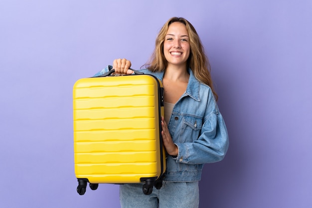 Junge blonde Frau isoliert im Urlaub mit Reisekoffer