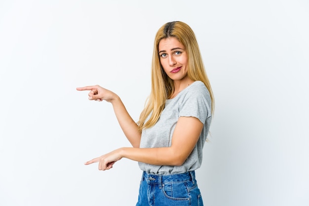 Junge blonde Frau lokalisiert auf weißem schockiertem Zeigen mit Zeigefingern auf einen Kopienraum.