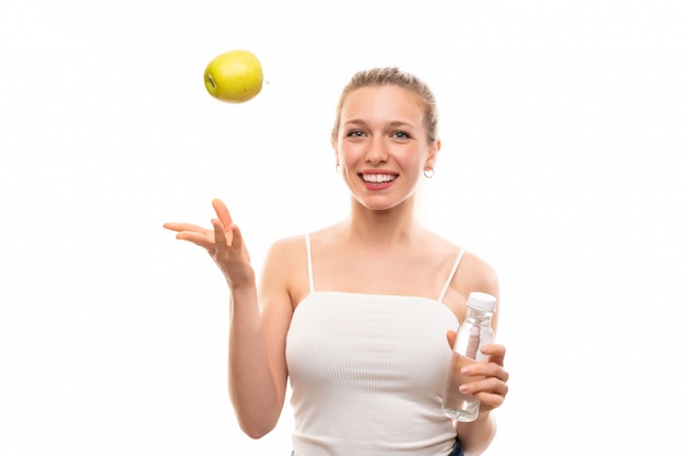 Junge blonde Frau mit einem Apfel und einer Flasche Wasser