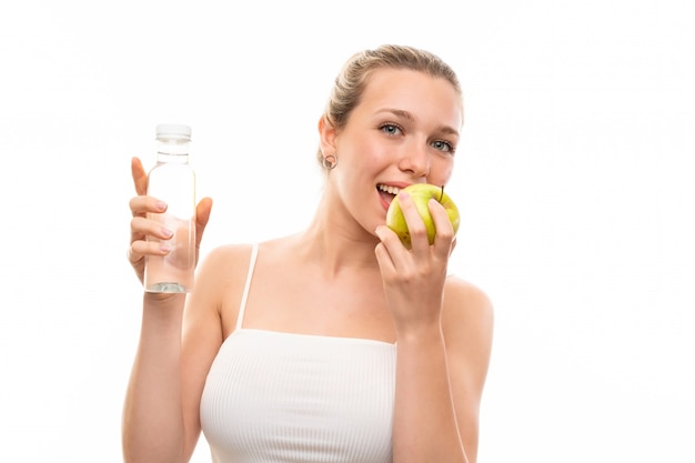 Junge blonde Frau mit einem Apfel und einer Flasche Wasser