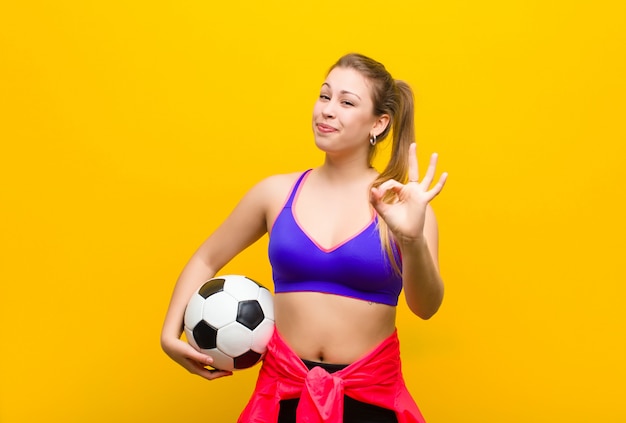 Junge blonde Frau mit einem Fußball. Sportkonzept