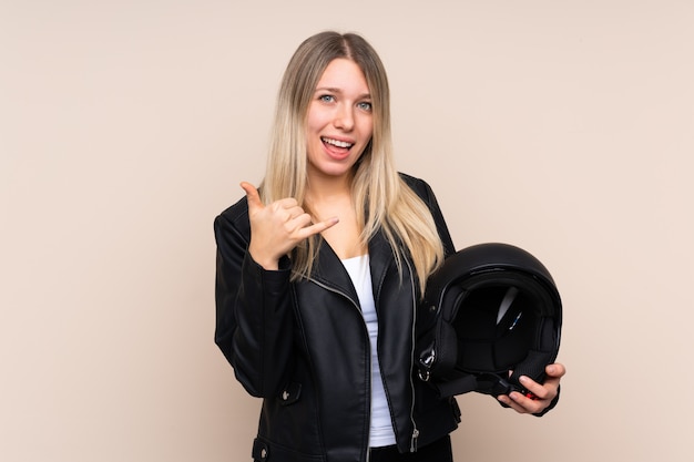 Junge blonde Frau mit einem Motorradhelm, der Telefongeste macht