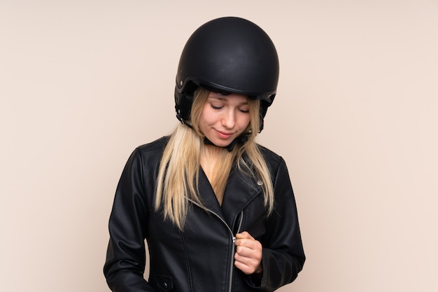 Junge blonde Frau mit einem Motorradhelm über isolierter Wand