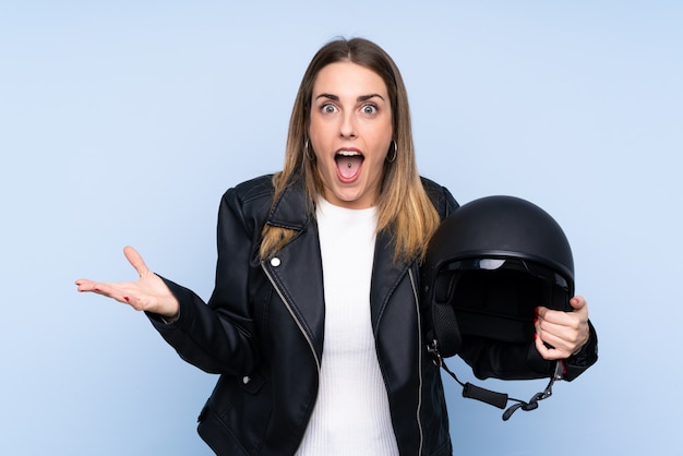 Junge blonde Frau mit einem Motorradsturzhelm über getrennter Wand mit entsetztem Gesichtsausdruck