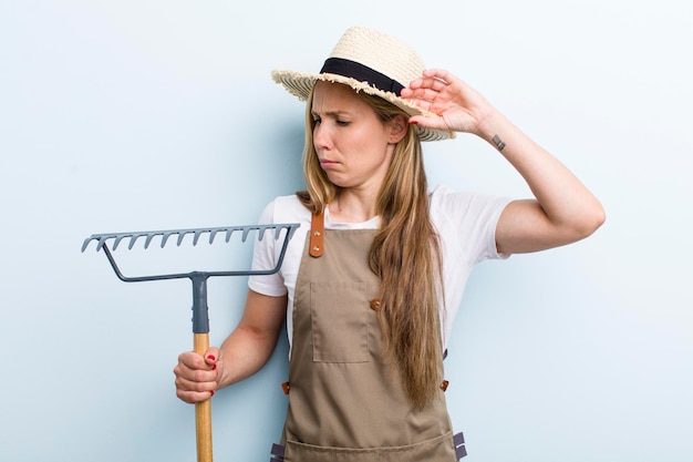 Junge blonde Frau mit einem Rake Farmer-Konzept