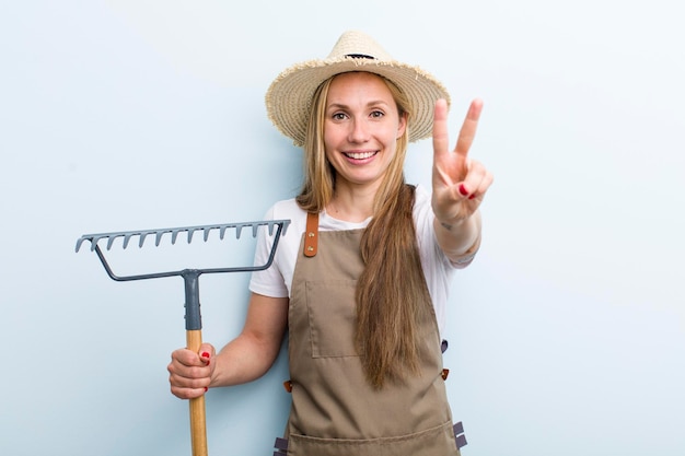 Junge blonde Frau mit einem Rake Farmer-Konzept