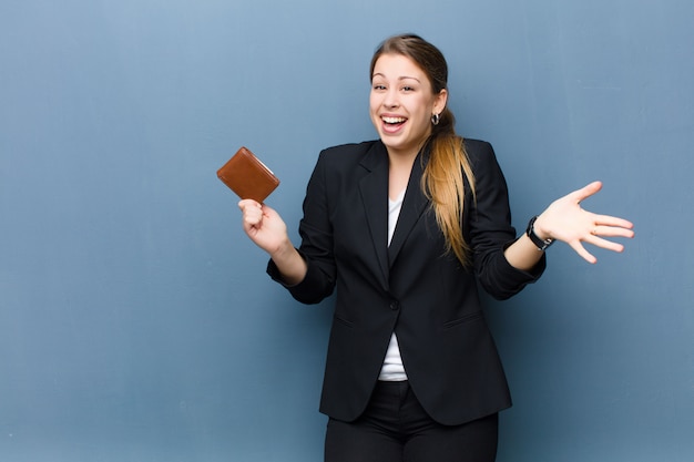 Junge blonde Frau mit einer Brieftasche gegen Schmutzwandhintergrund