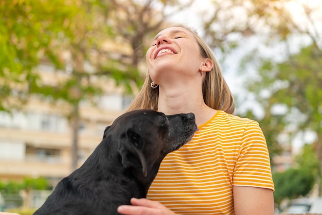 Junge blonde Frau mit ihrem liebenswerten schwarzen Hund im Freien