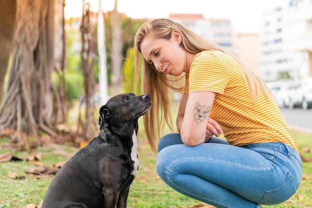 Junge blonde Frau mit ihrem liebenswerten schwarzen Hund im Freien