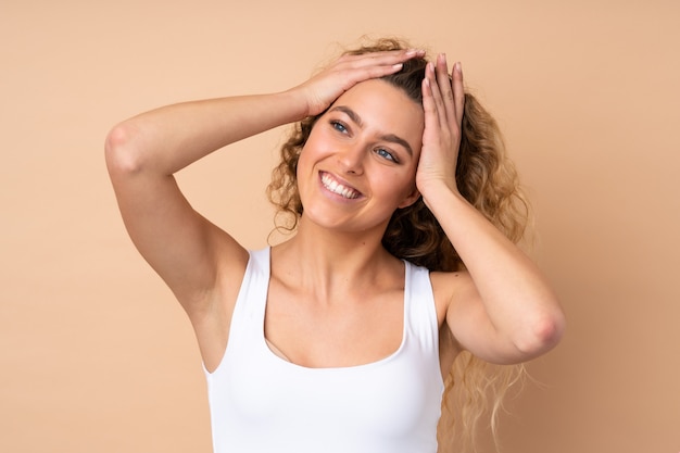 Junge blonde Frau mit lockigem Haar auf Beige. Porträt