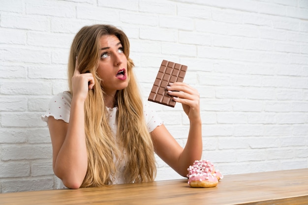 Junge blonde Frau mit Schokoladendenken