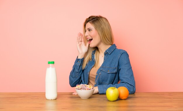 Junge blonde Frau mit Schüssel Getreide mit weit offenem Mund schreiend