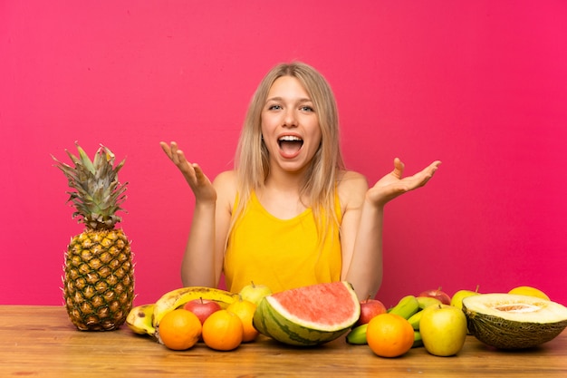 Junge blonde Frau mit vielen Früchten unglücklich und mit etwas frustriert