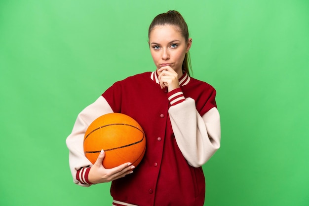 Junge blonde Frau spielt Basketball über isoliertem Chroma-Key-Hintergrunddenken