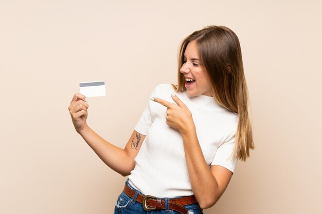 Junge blonde Frau über der getrennten Wand, die eine Kreditkarte anhält