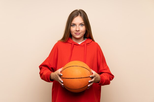 Junge blonde Frau über getrenntem Hintergrund mit Kugel des Basketballs