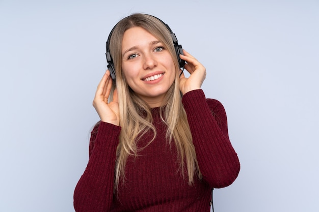 Junge blonde Frau über getrennter hörender Musik der blauen Wand